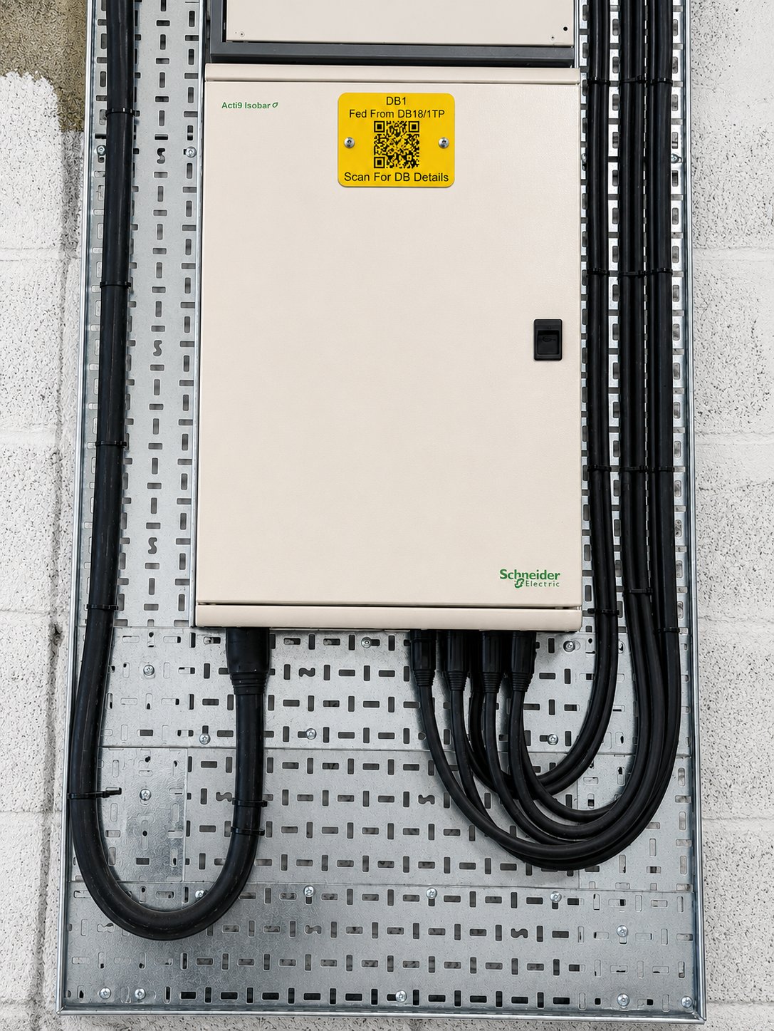 Schneider Acti9 distribution board with a yellow Lutrom QR nameplate reading 'DB1 — Fed From DB18/1TP — Scan For DB Details', mechanically attached and ready to scan
